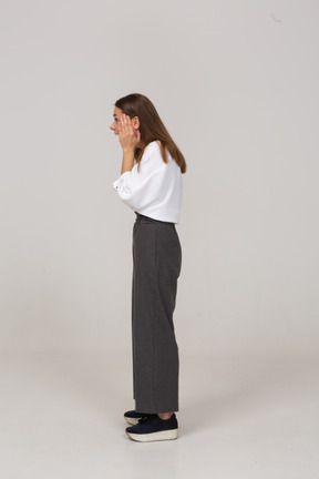 Side view of an excited young lady in office clothing touching face