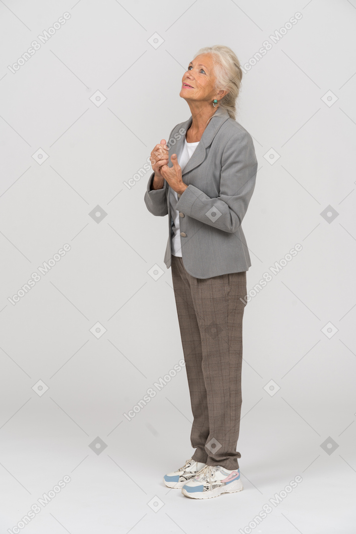 Vista laterale di una vecchia signora felice in abito che guarda in alto