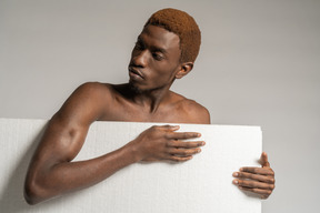 Front view of a young afro man standing behind styrofoam