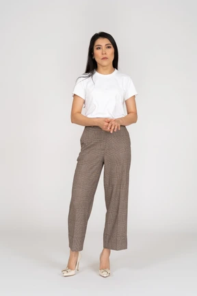 Front view of a serious young lady in breeches and t-shirt holding hands together