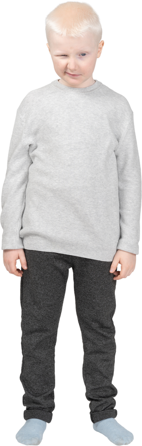 Puzzled kid boy standing still in grey sweater screwing lips