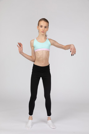 Vista frontal de una jovencita en ropa deportiva inclinando los hombros y haciendo olas