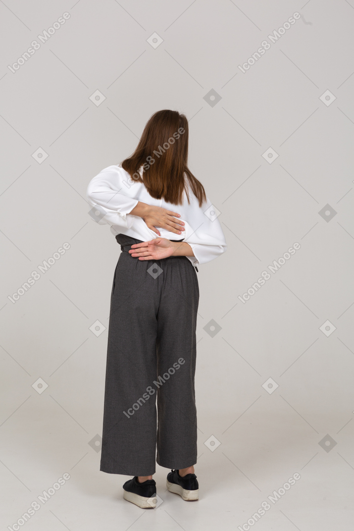 Vista posteriore di una giovane donna in abiti da ufficio con mal di schiena