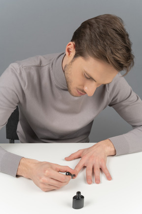 A young man is polishing his nails