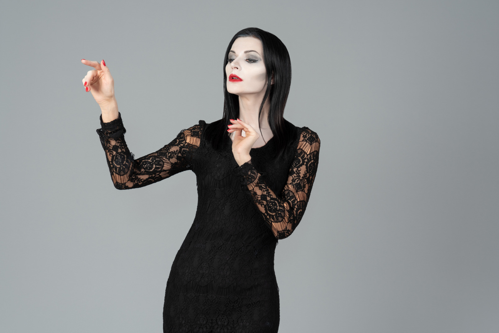 Morticia addams looking pensive and standing with her hands folded