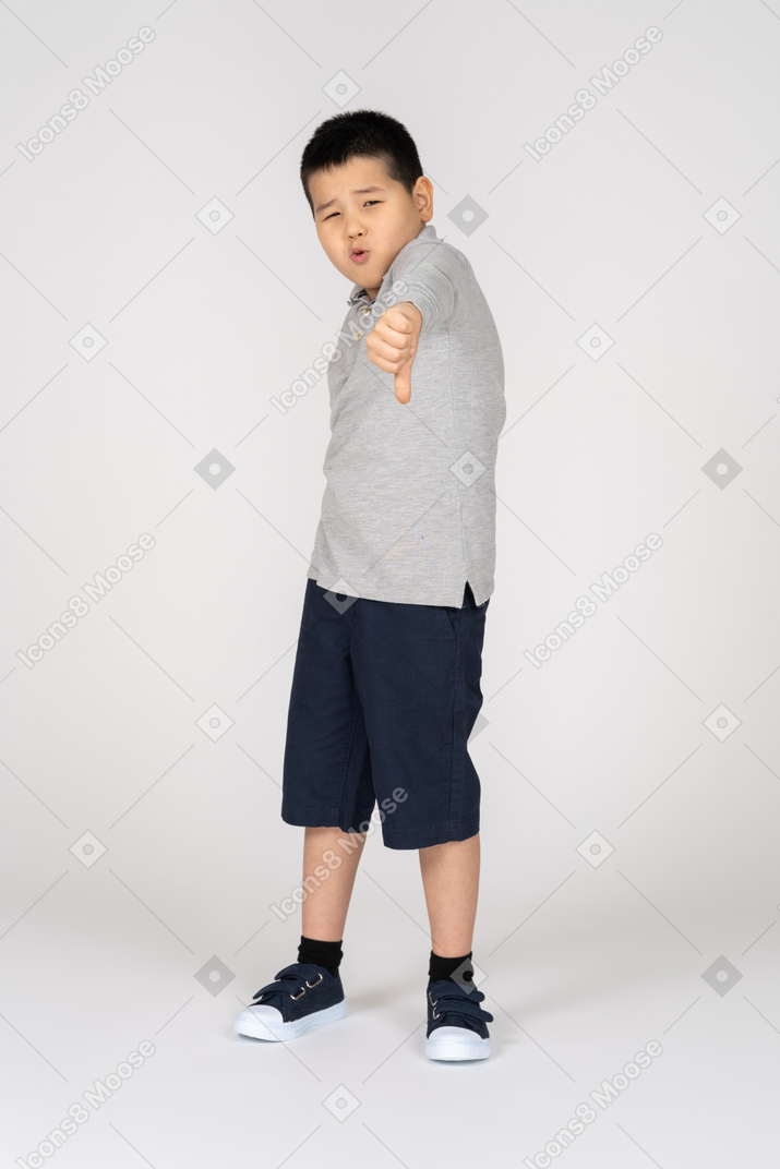 Boy giving thumb down and looking at camera