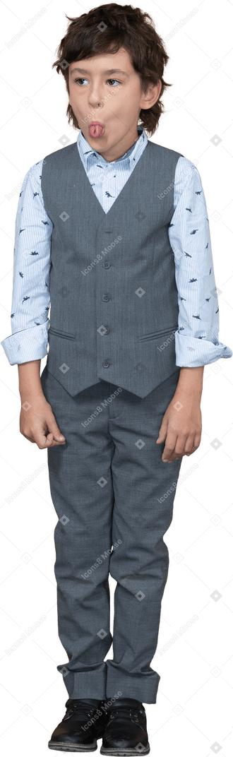 Вид спереди симпатичного мальчика в костюме, показывающего язык