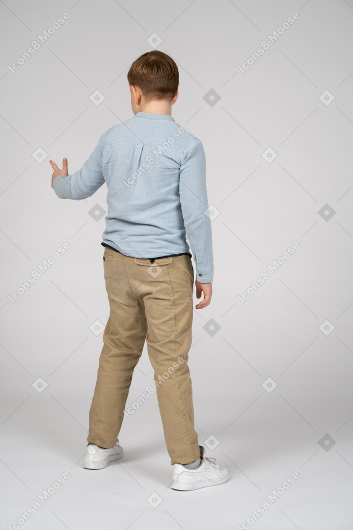 Niño parado de espaldas a la cámara y señalando algo