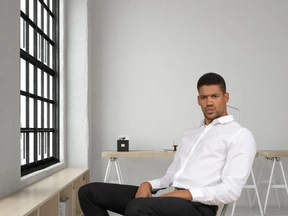 A man in a white shirt sitting on a chair in an office