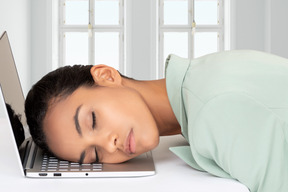 A woman sleeping on top of a laptop