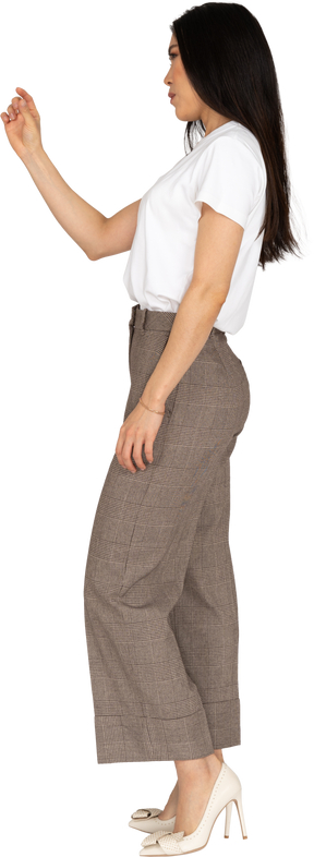 Vista laterale di una giovane donna in calzoni e maglietta bianca che mostra una dimensione di qualcosa