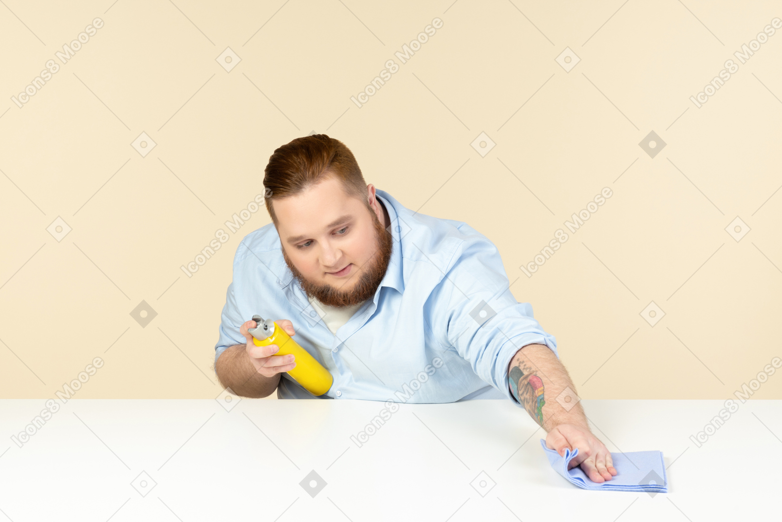 Homem jovem com excesso de peso, limpeza de superfície com spray de limpeza e um pano