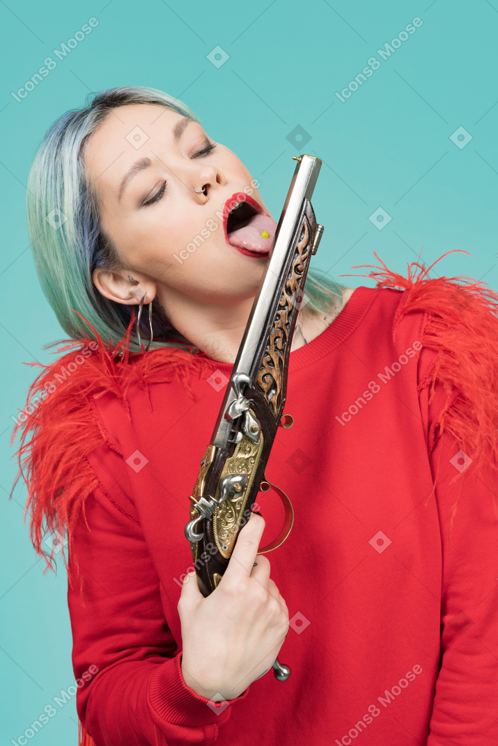Attractive young woman licking a gun