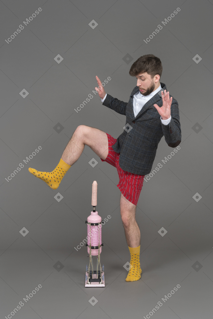 Young man stepping over a pink dildo