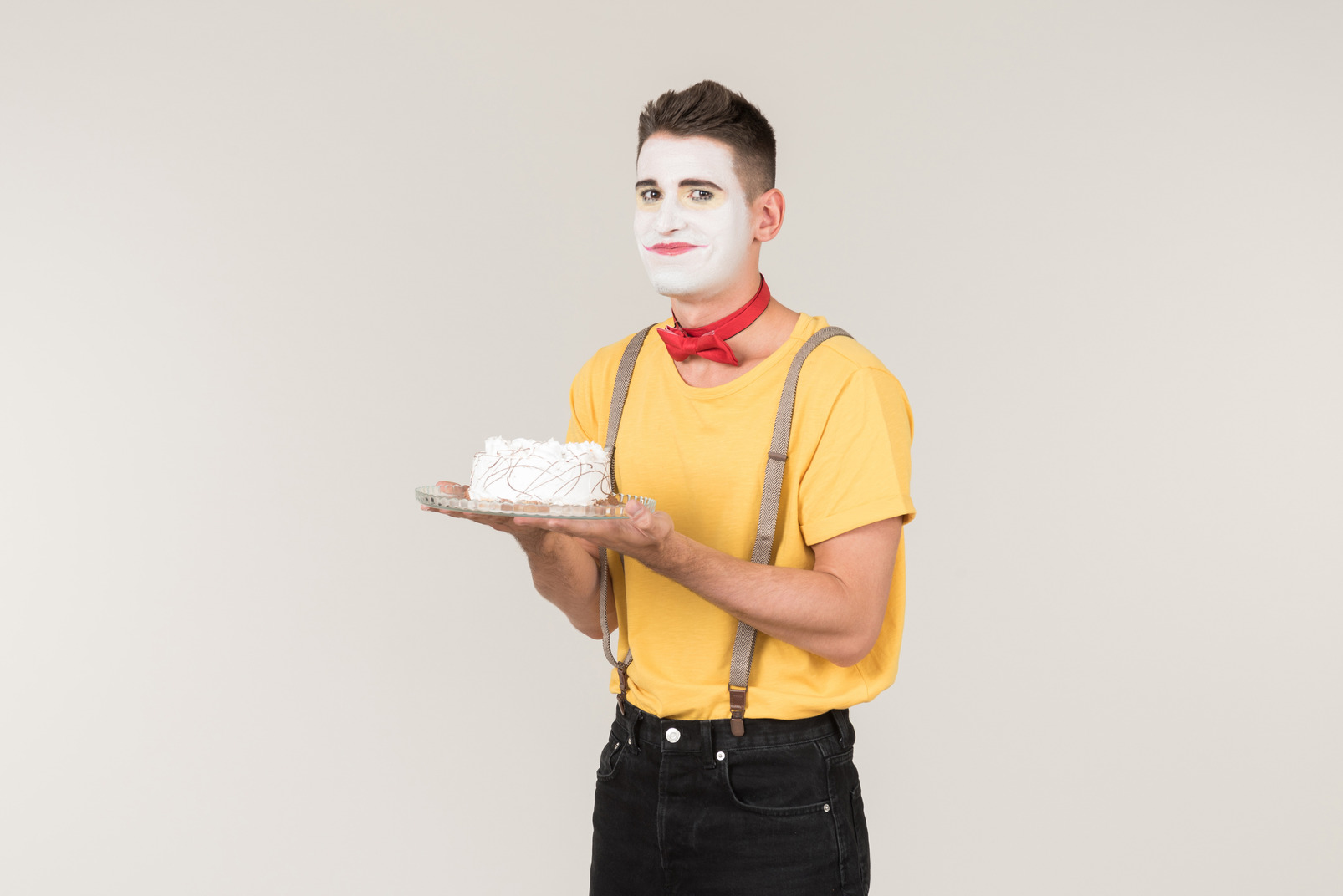 Male clown holding a white cake