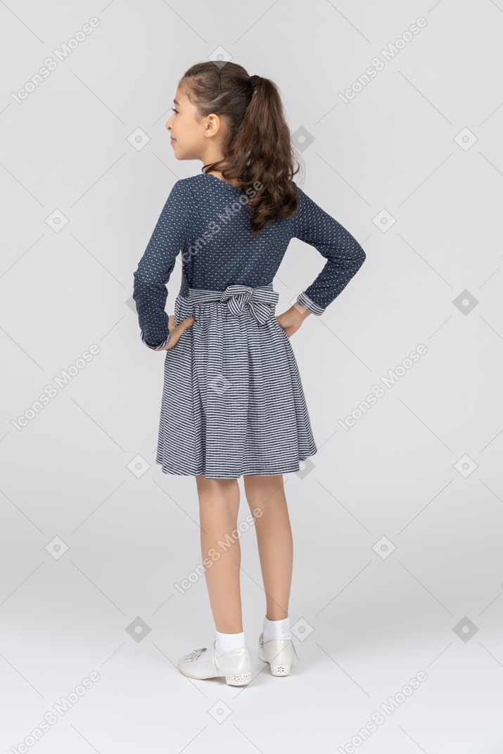 Three-quarter back view of a girl holding hands on her hips