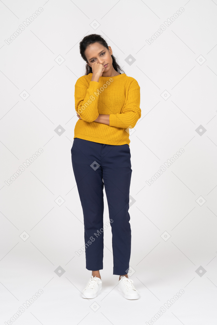 Front view of a bored girl in casual clothes holding fist on cheek and looking down