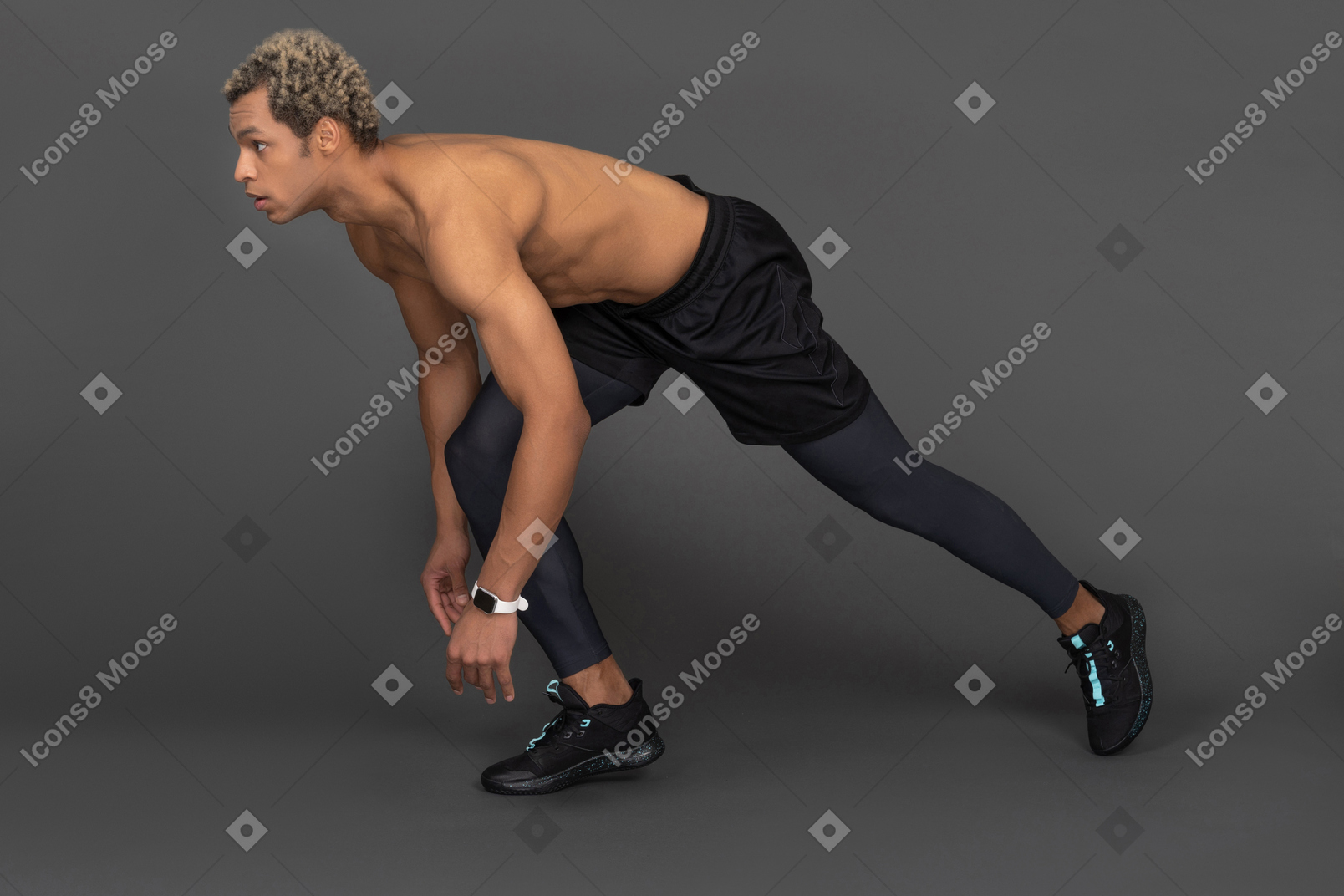 Side view of a shirtless dark-skinned sprinter ready to run
