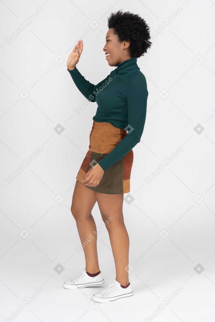 Cheerful teenage african-american girl waving hello in profile
