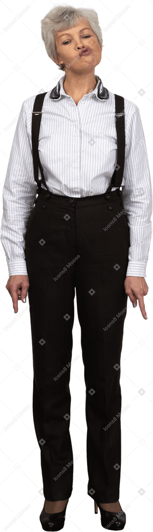 Front view of an old grimacing female in office clothes pointing down