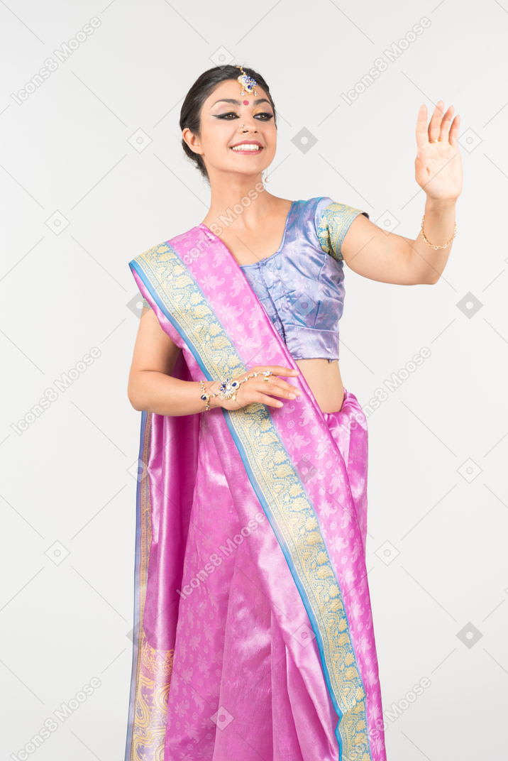 Young indian woman in purple sari waving with a hand
