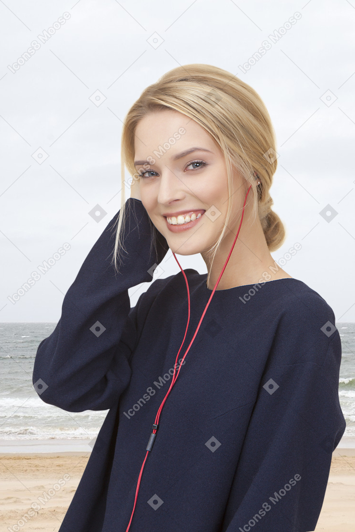 Young smiling woman in headphones at the beach