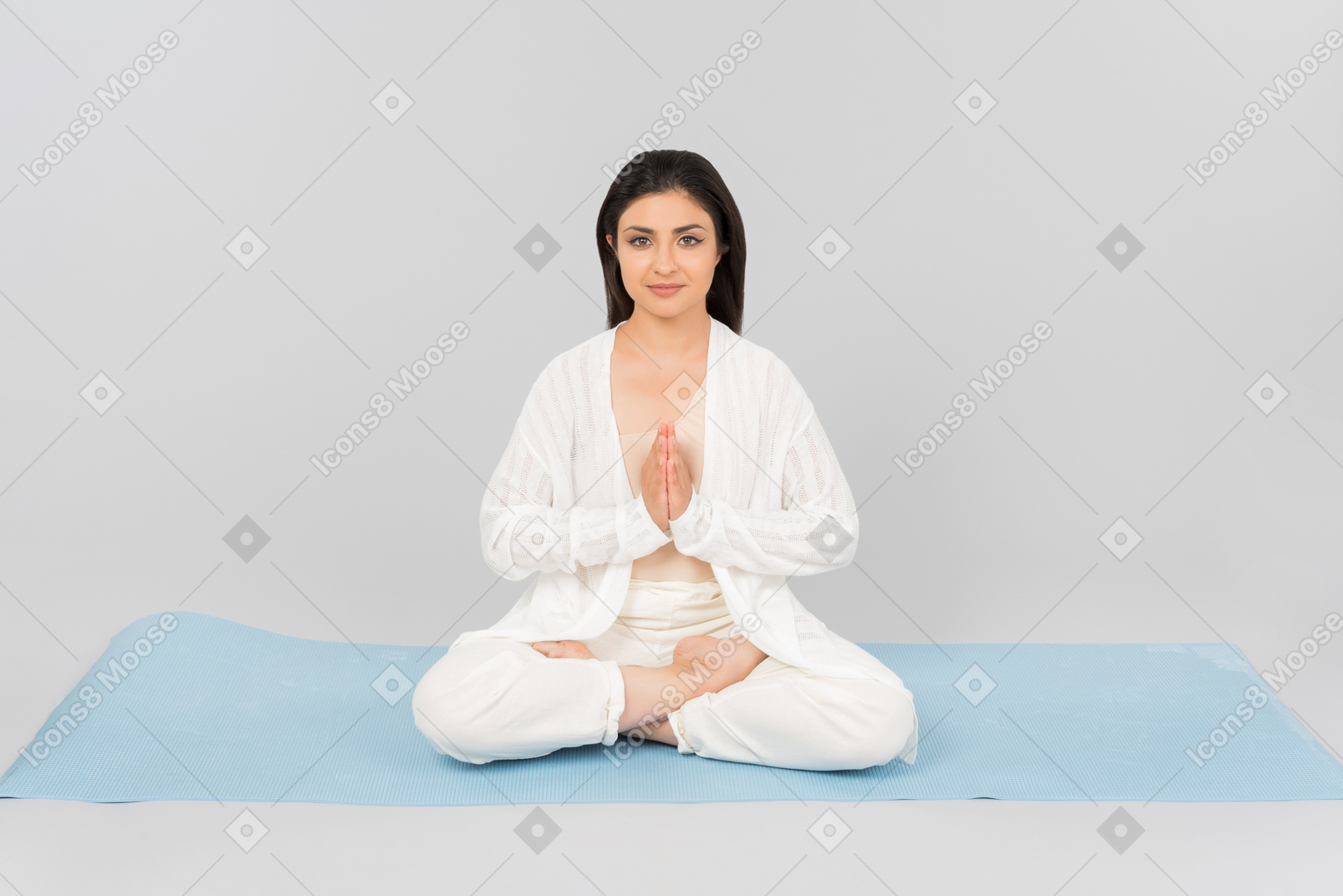 Young indian woman with hands folded and legs crossed sitting on yoga mat