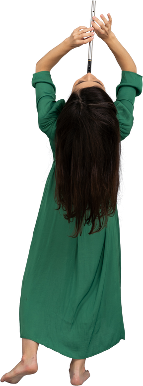 Vista posterior de una señorita en vestido verde tocando la flauta mientras se inclina hacia atrás