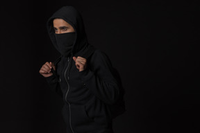 Hacker guy with covered face standing in the dark