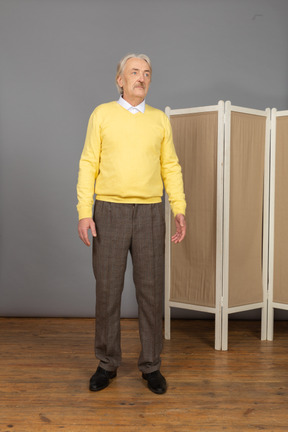 Front view of an old man standing still and looking aside