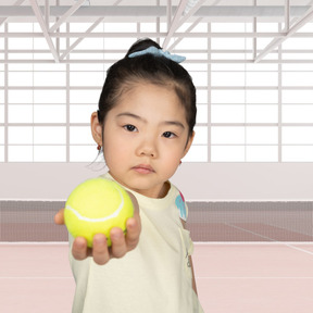 A little girl holding a tennis ball