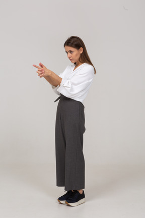 Vista di tre quarti di una giovane donna in abiti da ufficio che fa uno scatto