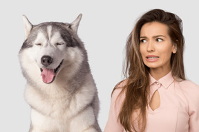 A woman standing next to a husky dog