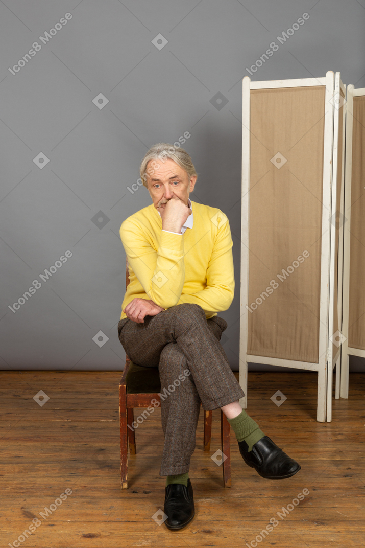 Man sitting cross-legged with his hand on his chin
