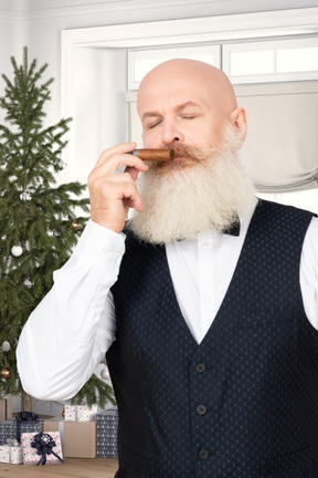 A man with a beard smelling a cigar