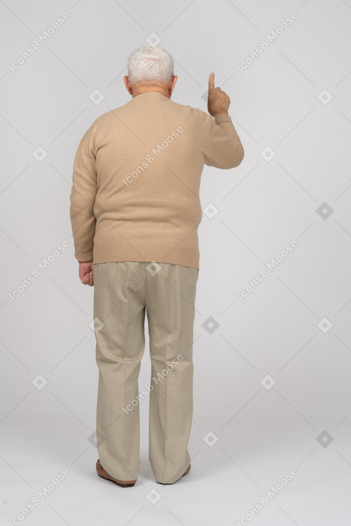 Rückansicht eines alten mannes in freizeitkleidung, der mit einem finger nach oben zeigt