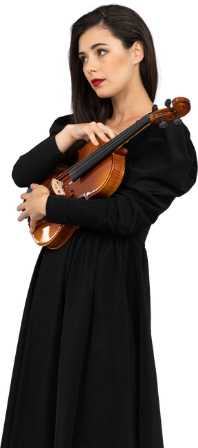 Vue de trois quarts d'une jeune femme en robe noire tenant le violon