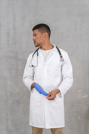 Young male doctor taking off nitrile gloves