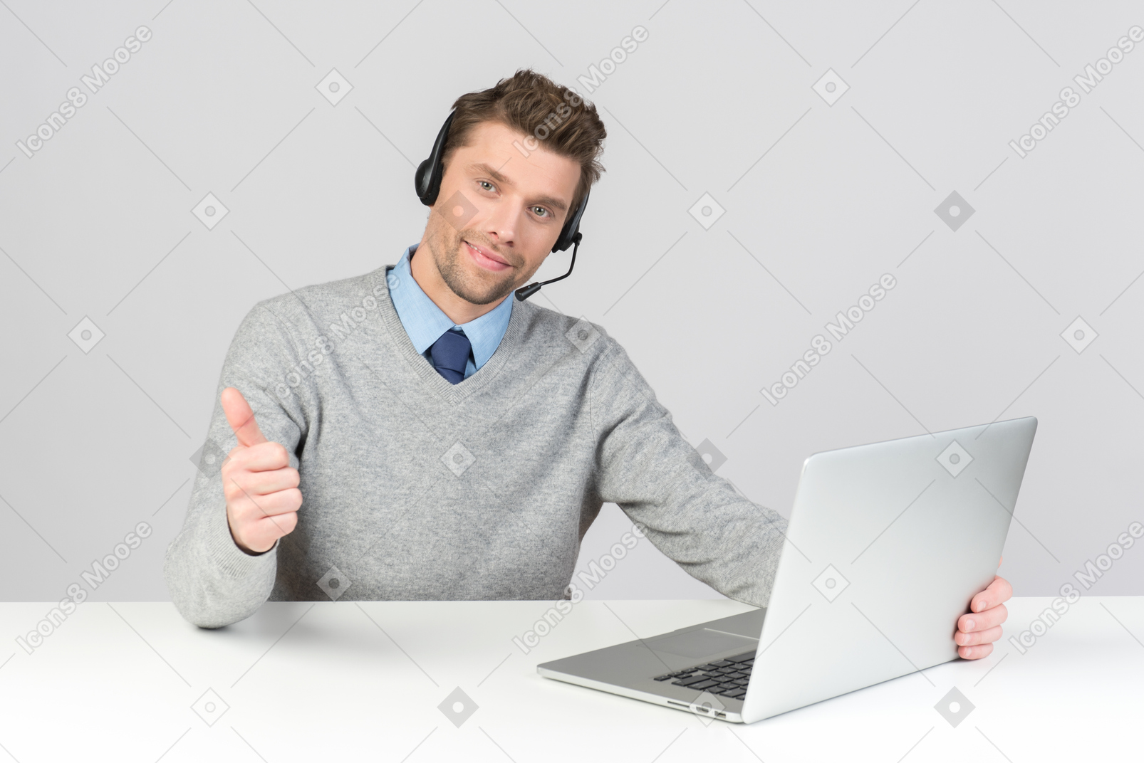 Call center agent sitting at the office desk and showing thumb up