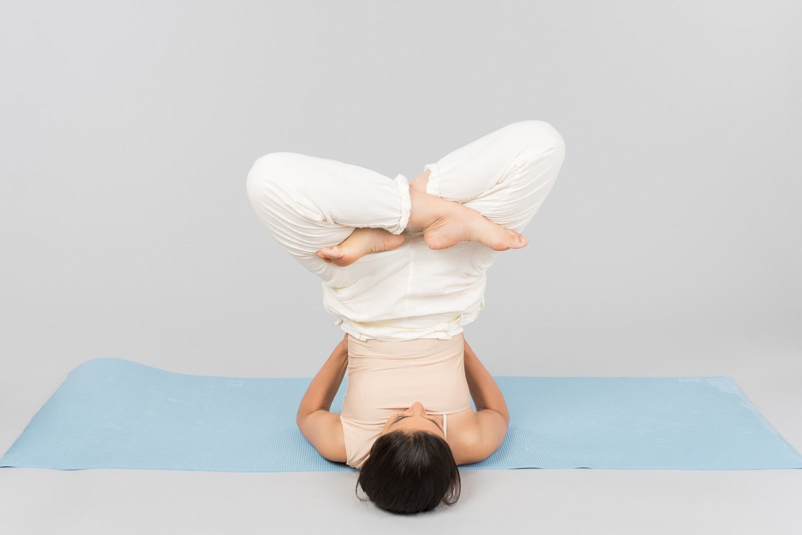 Young indian woman lying on head on yoga mat