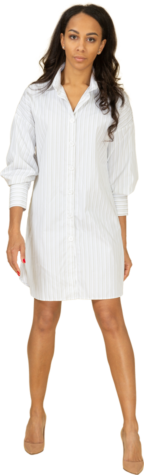 Vista frontal de una mujer joven de piel oscura confiada en vestido blanco
