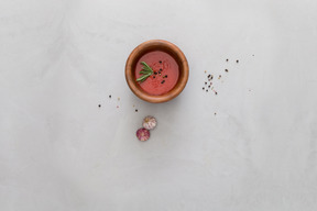 A bowl of gazpacho and some garlic