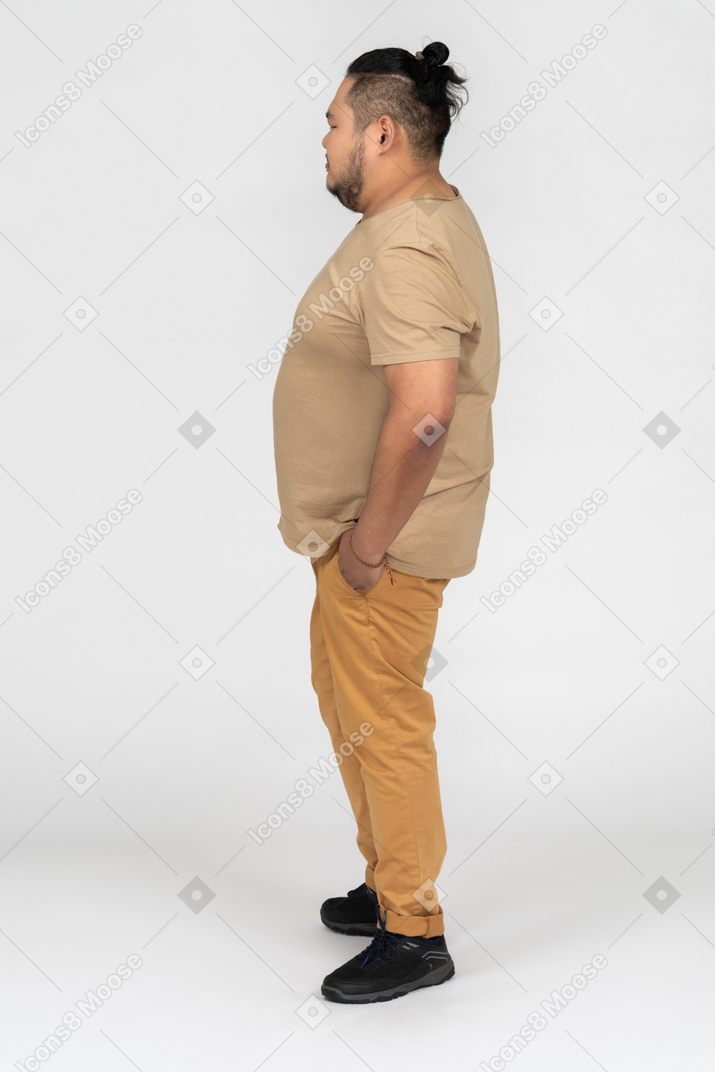 Asian man holding hands in pockets in profile