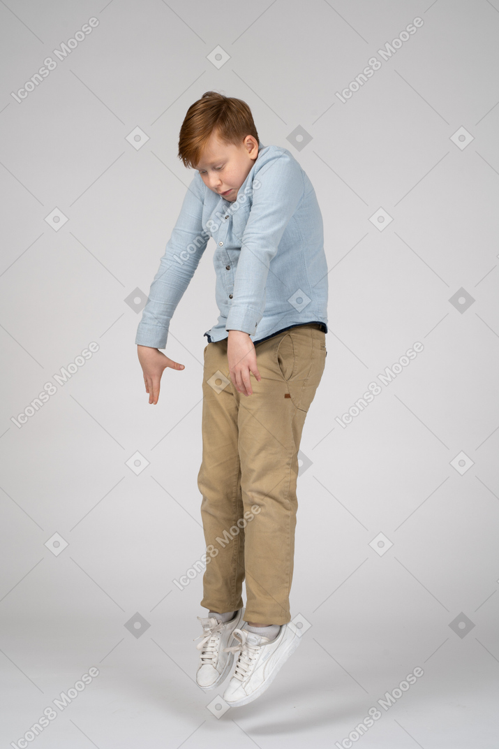Boy jumping up with hands reaching down