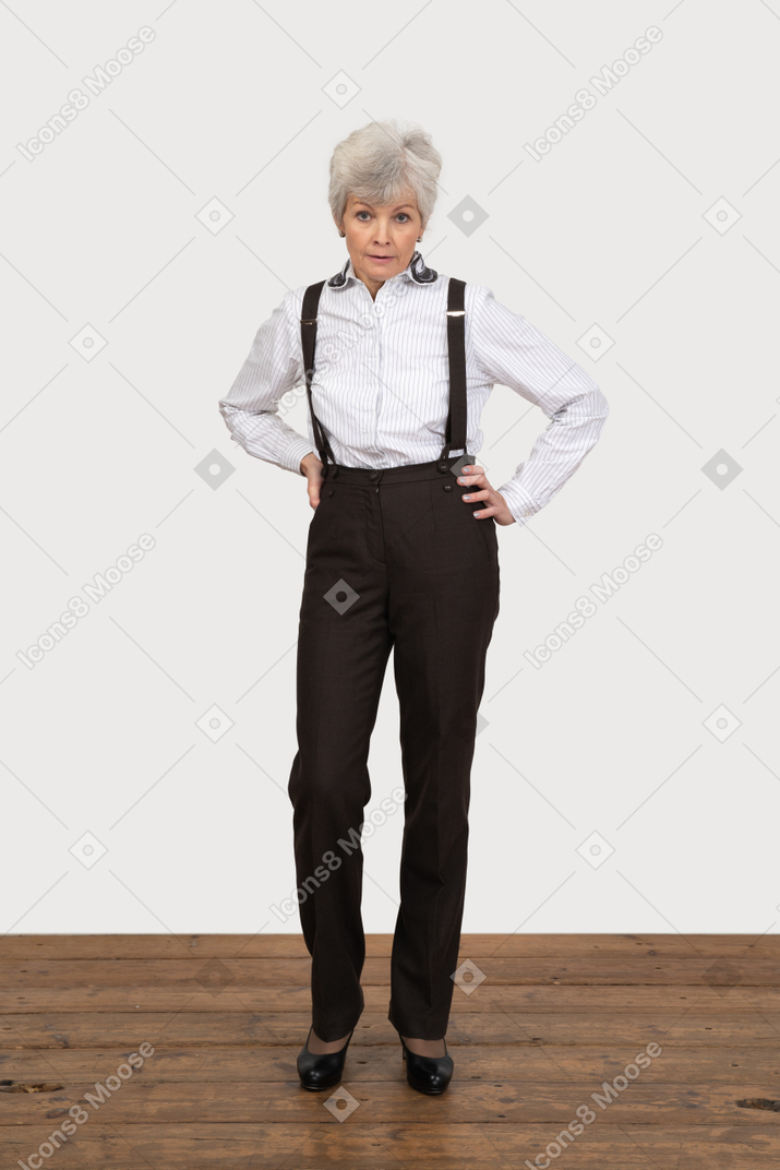 Front view of a displeased old lady in office clothing putting hands on hips