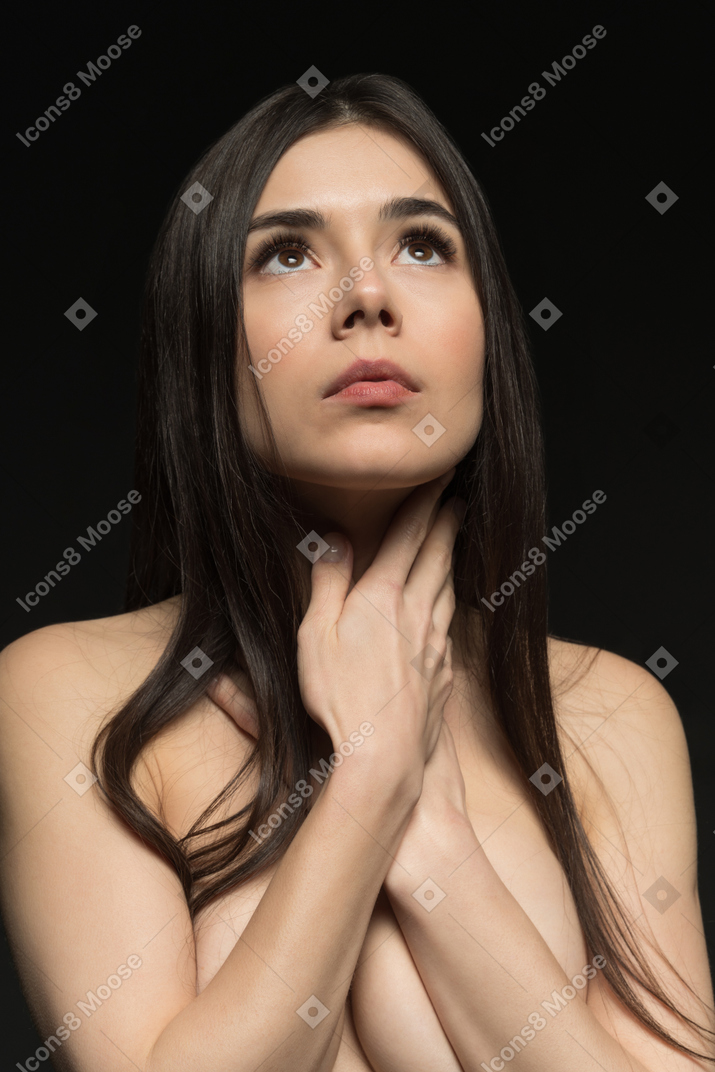 Front view of sensual naked young woman covering breast with hands