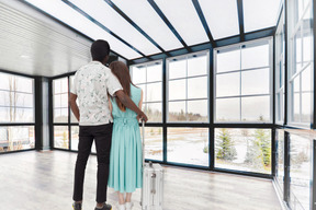 A man and woman standing in a large room with windows