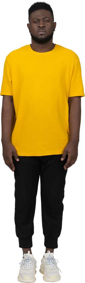 Front view of a young dark-skinned man in yellow t-shirt standing still