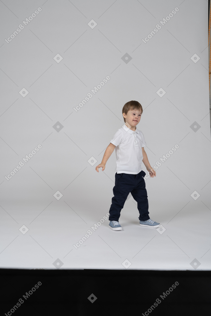 Маленький мальчик стоит с руками по бокам