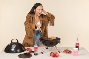 Joven asiática que tiene problemas con la barbacoa